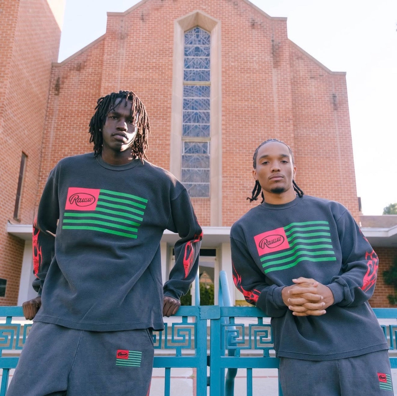 Two Raww Life models wearing the current drop in front of a brick building